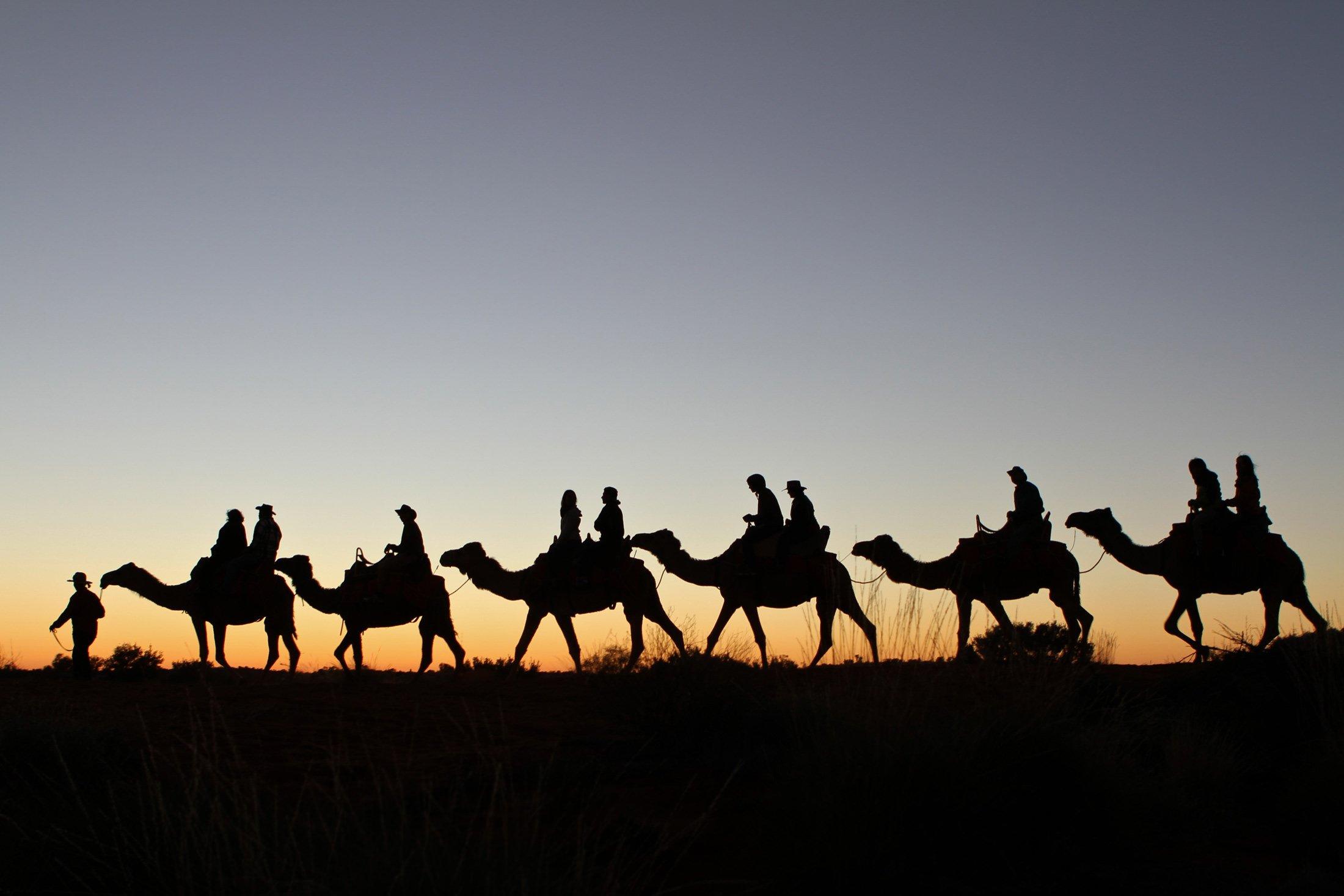 A silhouette of people riding camels at sunset | Uluru Australia | Uluru Rockies | Mossmangor Indigenous Tourism