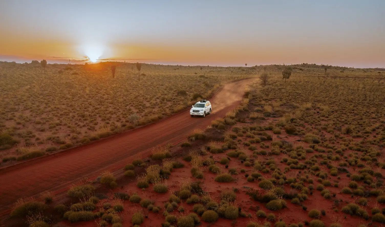 Car driving away from Uluru on road trip