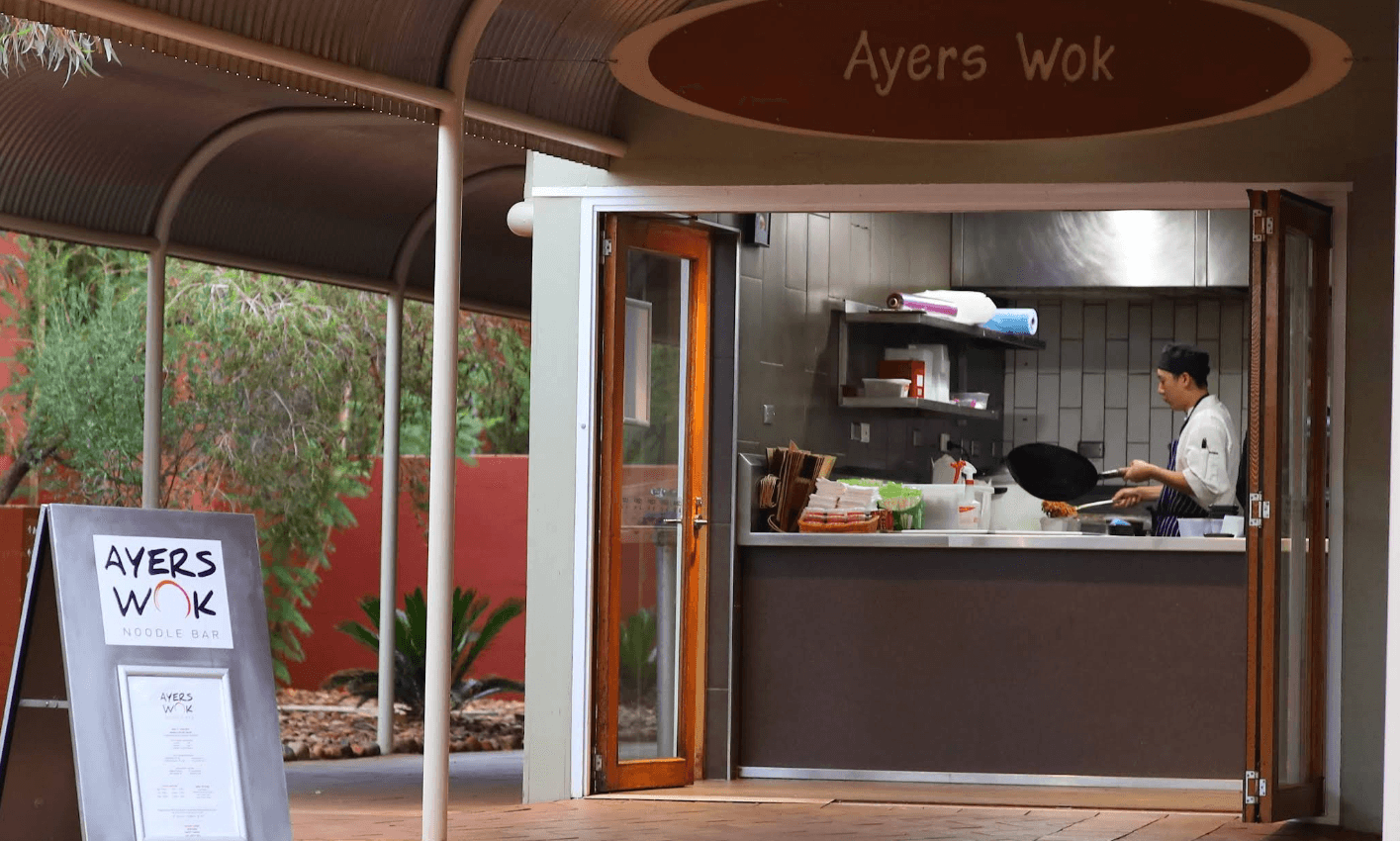 The entrance of Ayers Wok in Towns Square. There is menu outside and a man is cooking on a wok in the kitchen 