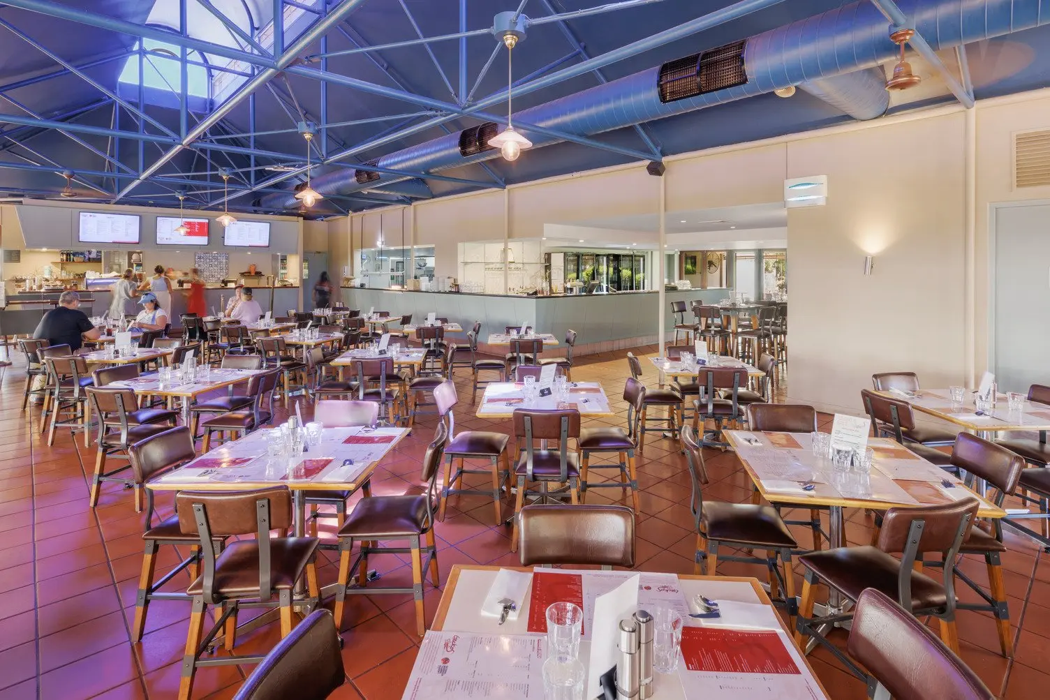 A panoramic shot of Geckos Cafe interior. Lots of tables and chairs with a bar and place to order food
