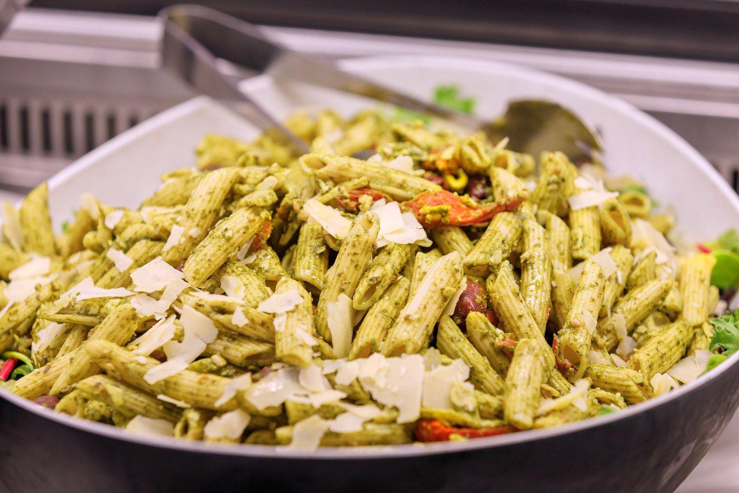 A bowl of pesto penne pasta in the buffet