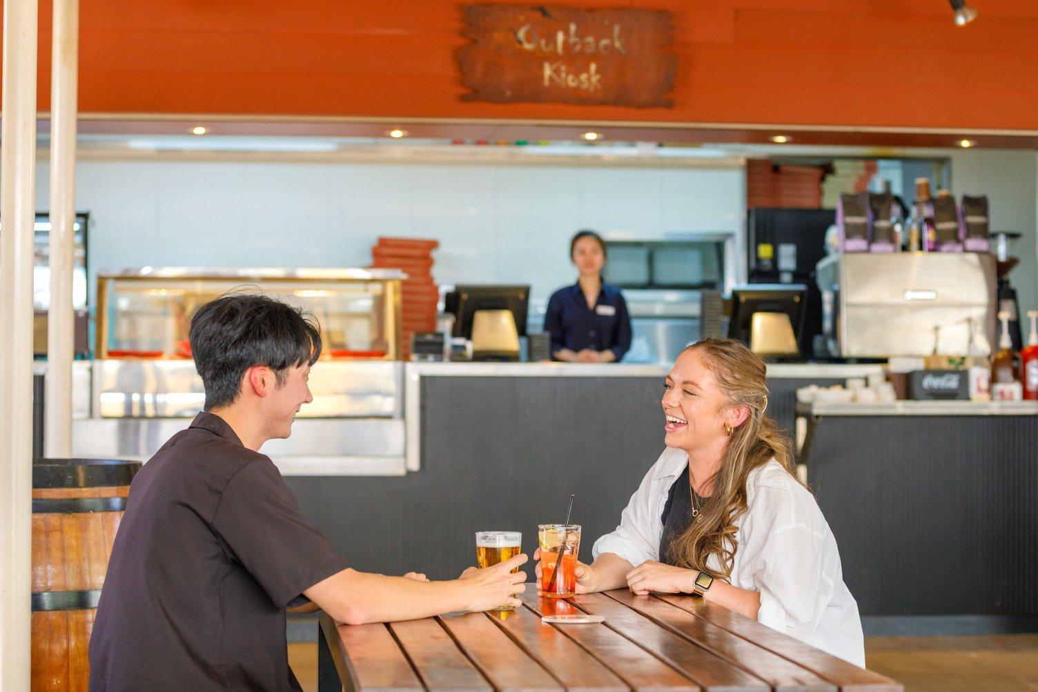 A women and a man having a drink in front of the Outback Kiosk