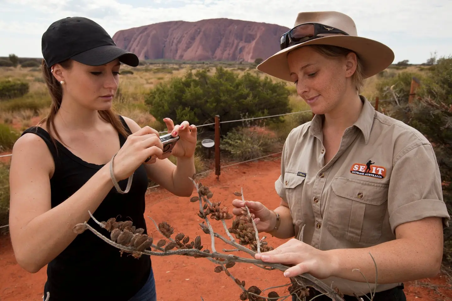 Woman taking a photo of plant being held by tour guide