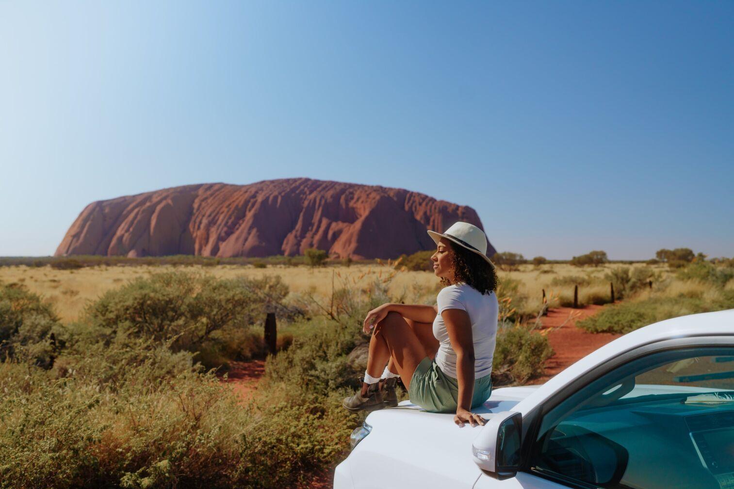 women-sitting-on-top-of-the-car-watching-uluru