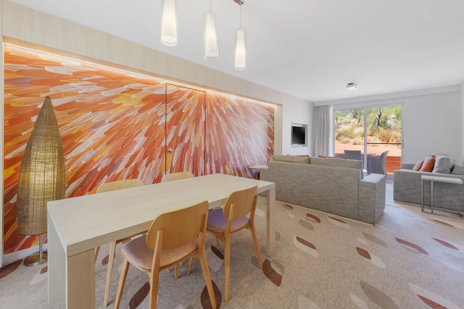 Dining area with a table and 4 chairs, and loungeroom with two grey couches and TV, looking out onto the courtyard