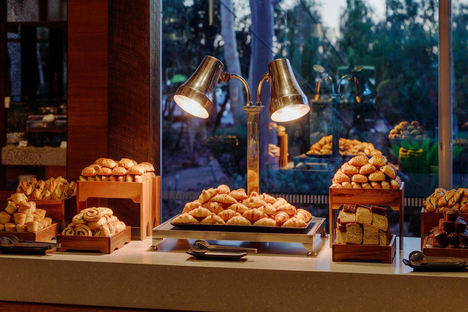An image of croissant and pastries lite up by two lamps at Ilkari Buffet Breakfast, Sails in the Desert.