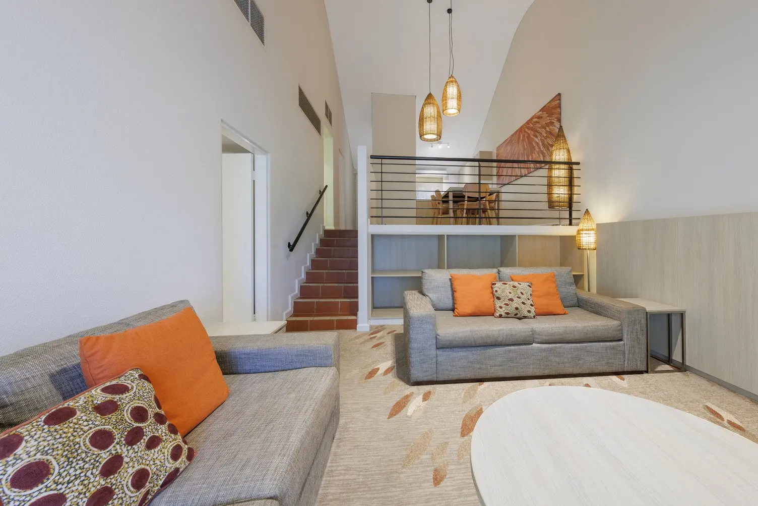 Loungeroom with two couches (1 fold out sofa to sleep on) with stairs leading up to the dining area and kitchen