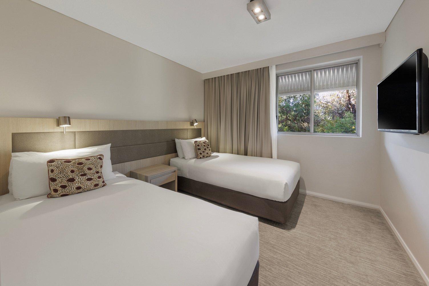 Bedroom with twin singles, TV mounted to wall and window looking out towards the garden