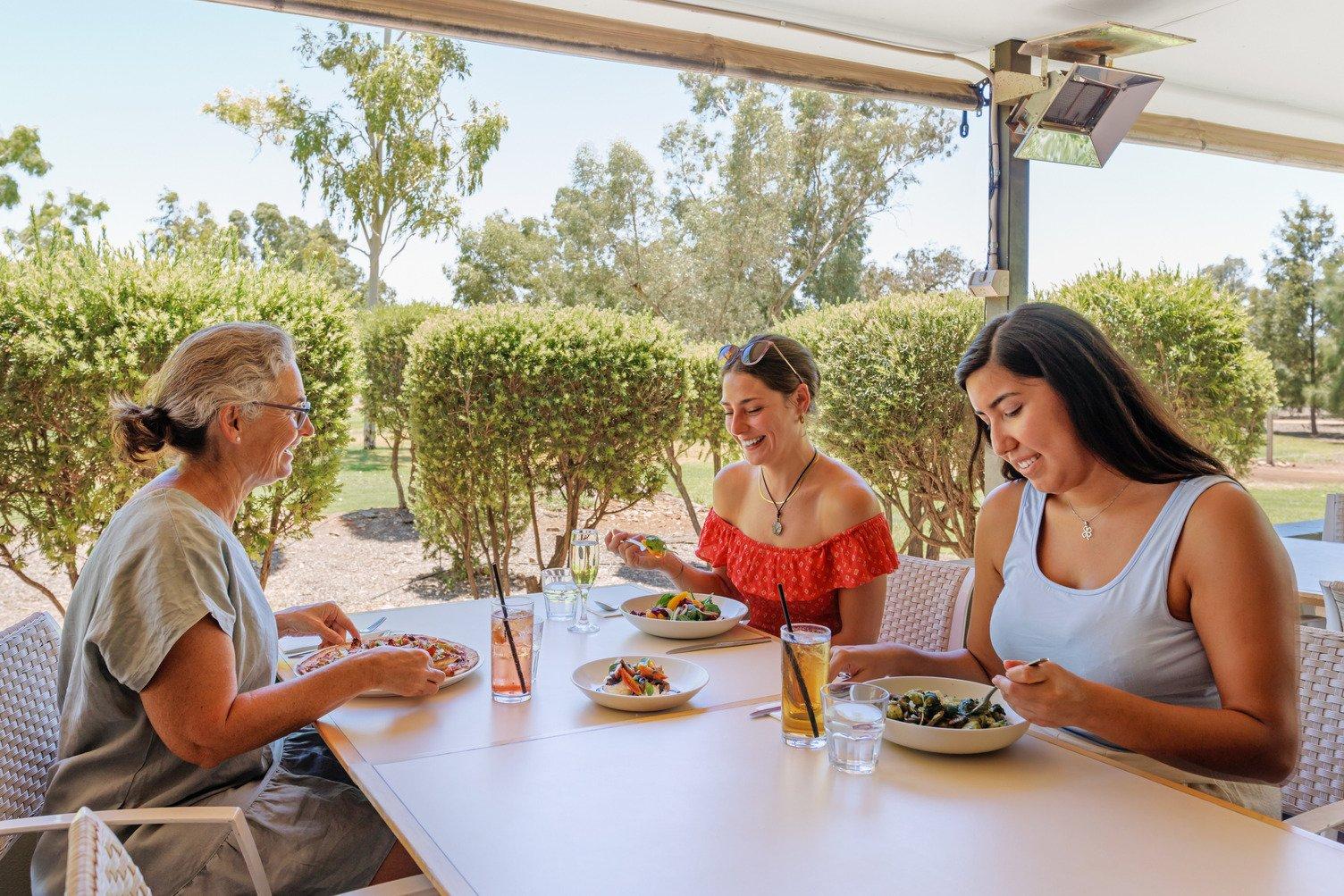2 young and 1 older lady sitting at a table eating a Chicken Avocado pizza, Beetroot and Fennel Salad and Chicken Alla Genovese with Gnocchi