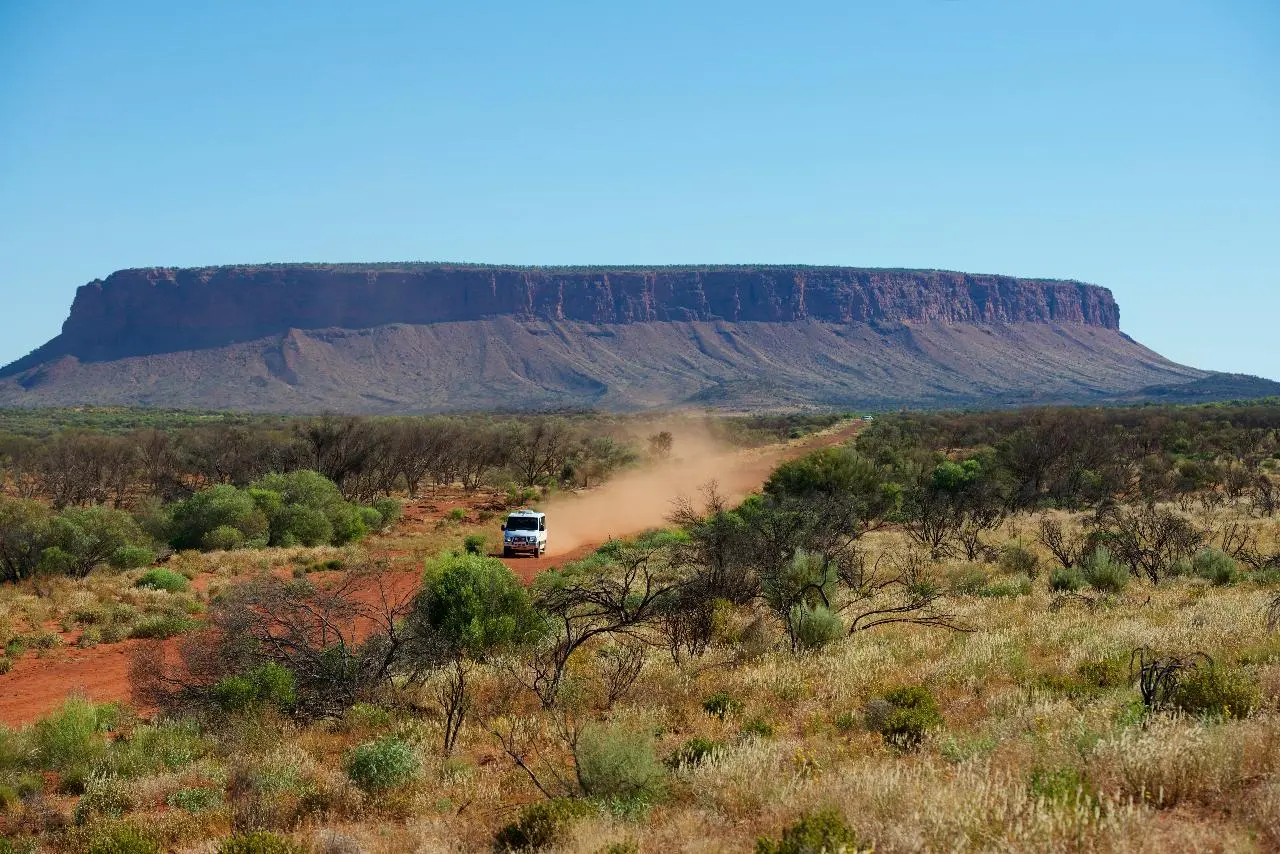 A car driving in front of Mt Conner in the Northern Territory