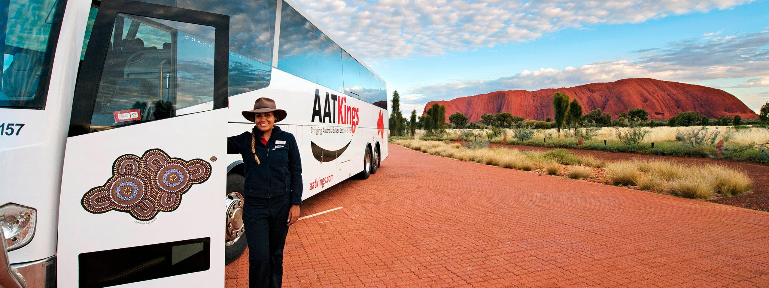 Driver guide standing next to AAT Kings coach in front of Uluru