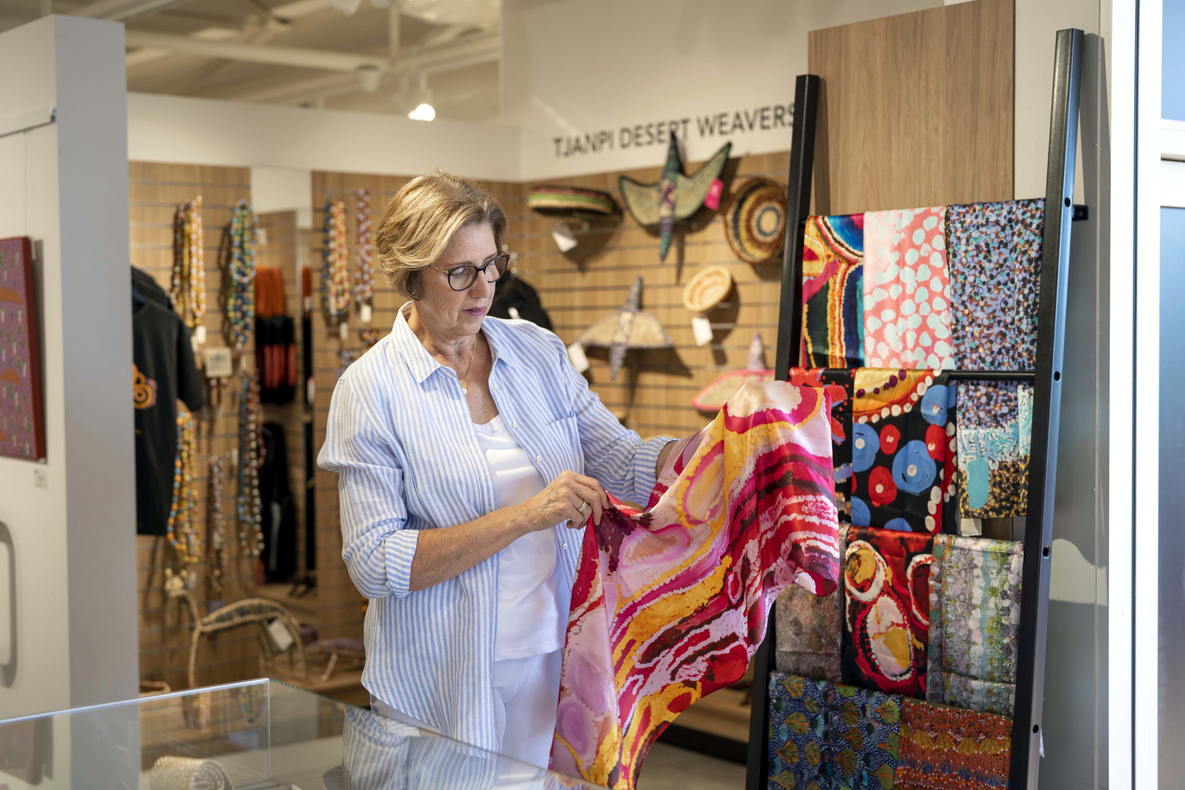 Woman browsing a colourful scarf in the Gallery of Central Australia, at Ayers Rock Resort