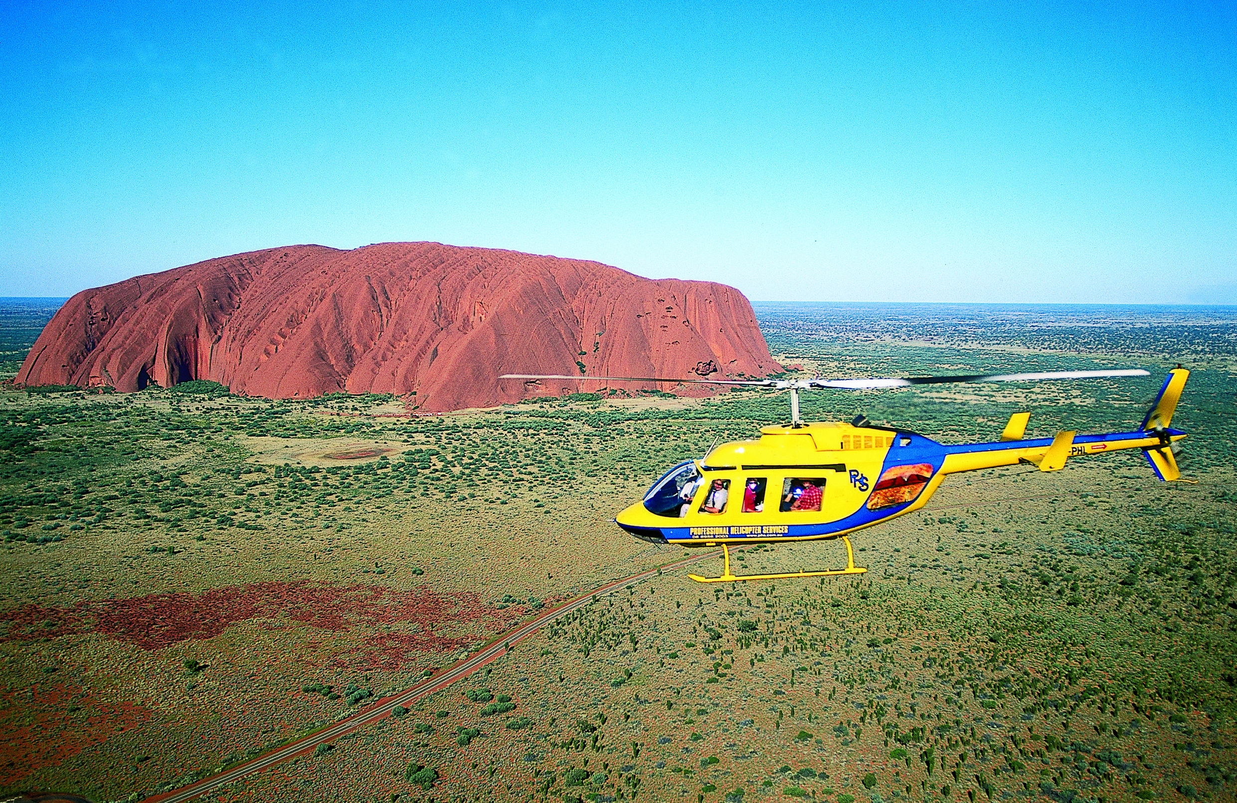 helicopter in flight by Ayers Rock