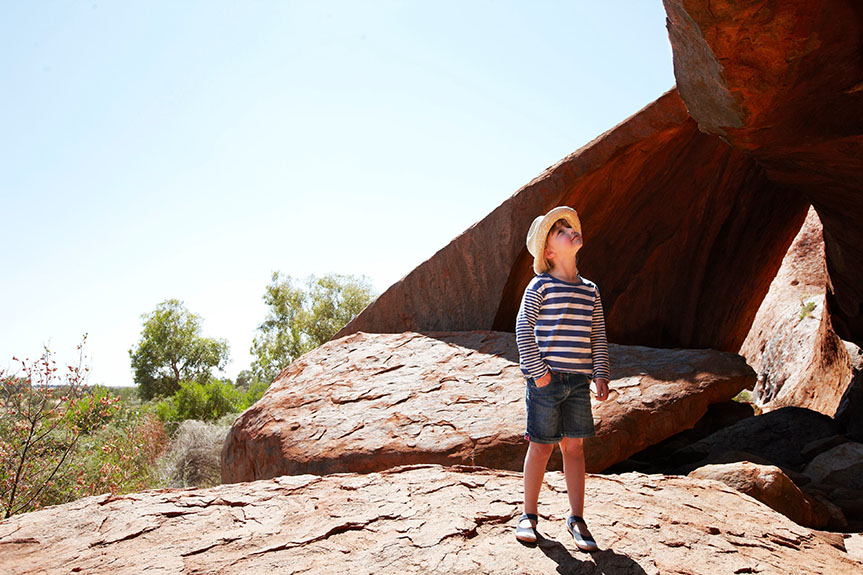 Young boy in hat and striped shirt looking at Ayers Rock