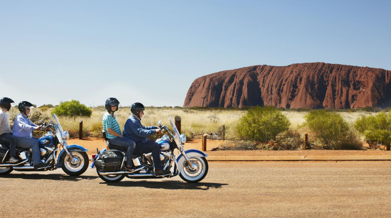 motorcycles driving past Uluru
