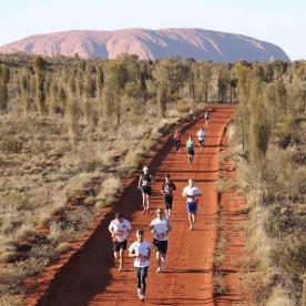 Runners compete in the Australian Outback Marathon with Uluru in the background