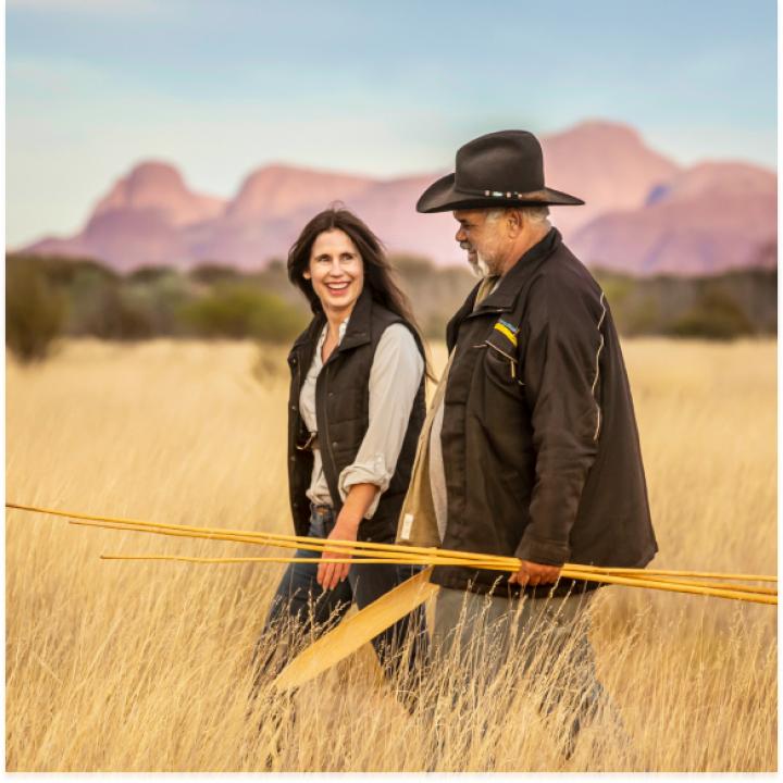 Two people walk together through the outback.