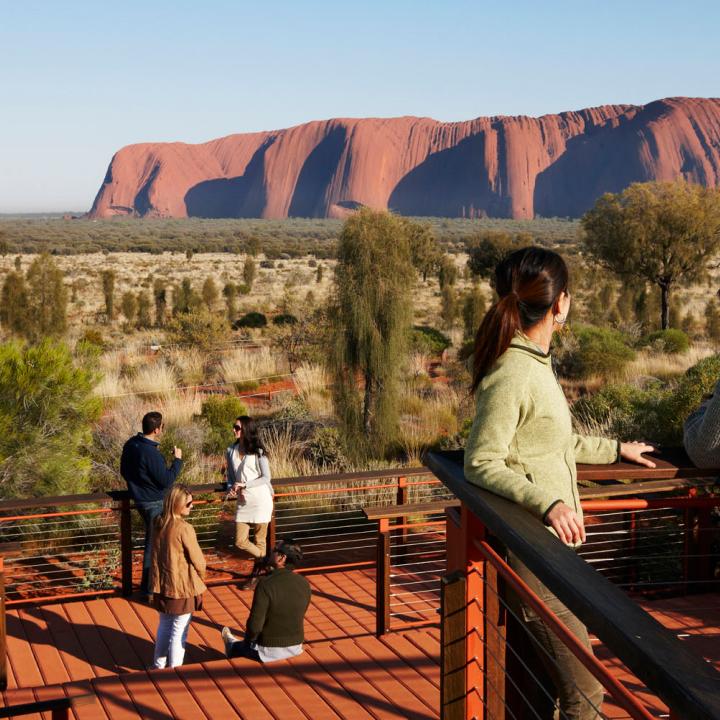 people on a deck with Ayers Rock in the background