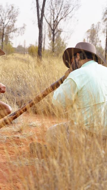 indigenous man playing the didgeridoo