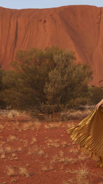Woman dancing in a dress in front of Uluru