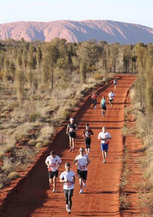 Runners compete in the Australian Outback Marathon with Uluru in the background